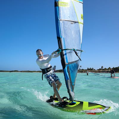 Mężczyzna na desce windsurfingowej na lazurowej wodzie na Bonaire podczas szkolenia Wavcamp