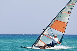 Windsurfer płynie w ślizgu na desce windsurfingowej podczas zajęć z Wavecamp na Rodos Prasonissi