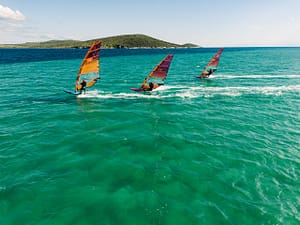 Uczestnicy obozu windsurfingowego Wavecamp płyną na deskach w Alacati w Turcji