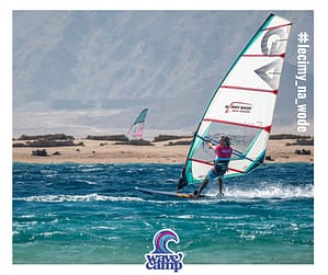 Instruktor windsurfingu Wavecamp płynie w pełnym ślizgu po lazurowej wodzie na desce windsurfingowej w Dahab w Egipcie
