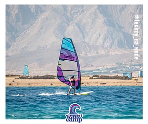 Kobieta na windsurfingu płynie w ślizgu po błękitnej wodzie podczas zajęć z instruktorem Wavecamp w Dahab