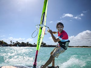 Wesoły windsurfer na desce śmieje się i robi zabawną minę