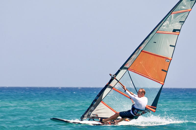 Windsurfer płynie w ślizgu na desce windsurfingowej podczas zajęć z Wavecamp na Rodos Prasonissi