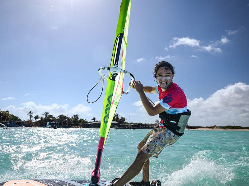 Wesoły windsurfer na desce śmieje się i robi zabawną minę