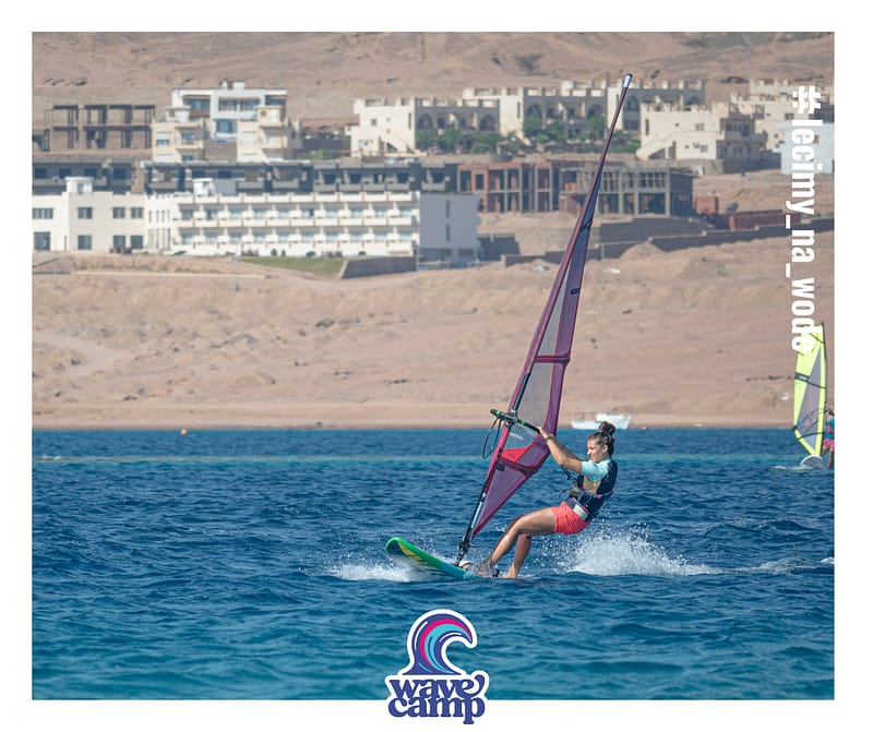 wyjazdy windsurfingowe dla singli, dziewczyna płynie na desce windsurfingowej na obozie Wavecamp w Egipt, Dahab